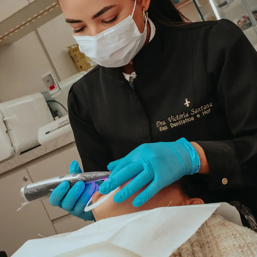 Dra. Victoria fotopolimerizando a resina no dente da paciente
